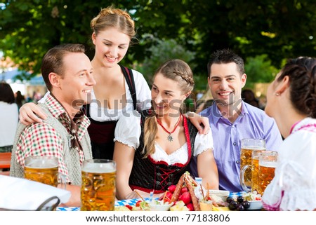 In Beer garden - friends Tracht, Dindl and on a table with beer and snacks in Bavaria, Germany
