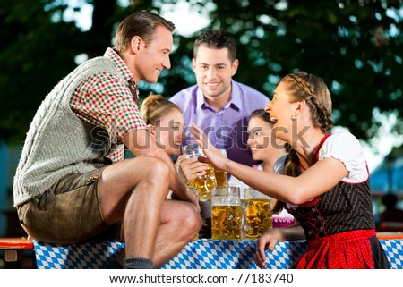 In Beer garden - friends in Lederhosen drinking a fresh beer in Bavaria, Germany