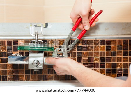 Plumber installing a mixer tap in a bathroom, only hands to be seen