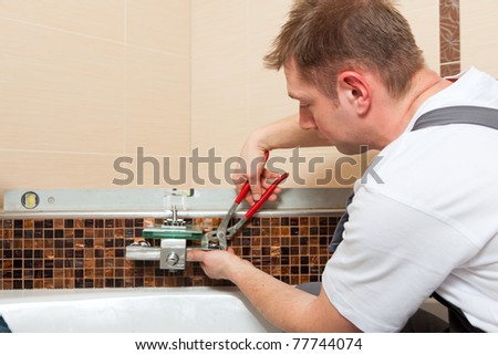 Plumber installing a mixer tap in a bathroom