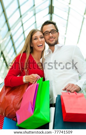 Couple - man and woman - in a shopping mall with colorful bags