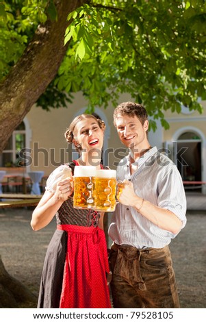 Couple with beer stein and traditional clothes in a beer garden