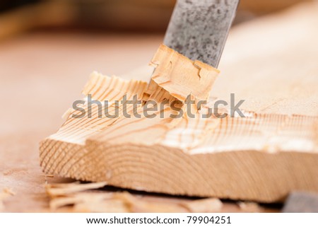Carpenter working with a chisel in his workshop; close-up on chisel
