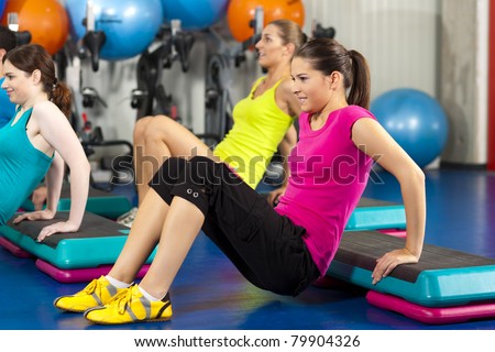 Fitness people in gym on step board; strengthening the abdominal muscles