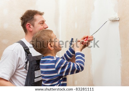 Father and son painting a wall in their home, they presumably do it in the course of moving in