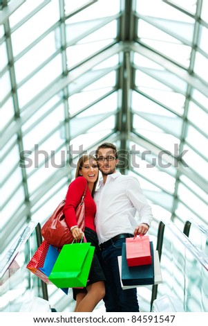 Couple - man and woman - in a shopping mall with colorful bags