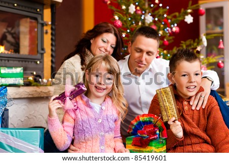 Christmas - happy family (parents with son and daughter) with gifts on Xmas Eve