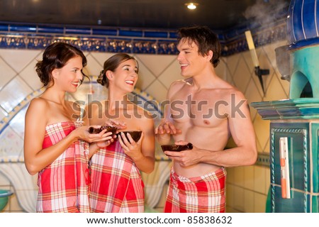 Three friends - two women, one man - doing wellness in the sauna of a thermal bath
