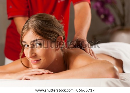 Woman enjoying a wellness back massage in a spa, she is very relaxed (close-up); the masseur could be her boyfriend