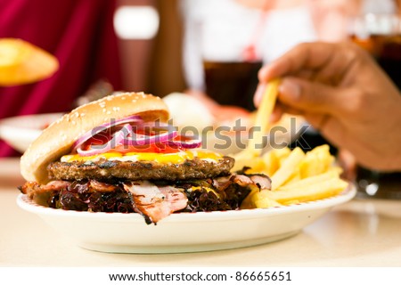 Fast food hamburger and fries in a restaurant on a dish - close-up and focus on the burger