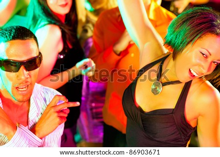 Dance action in a disco club - group of people, men and women of different ethnicity, dancing to the music having lots of fun