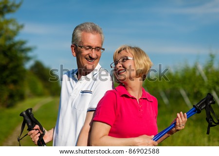 Nordic Walking - Happy mature or senior couple doing sports in summer outdoors