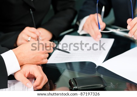 Business - meeting in an office; lawyers or attorneys (only hands) discussing a document or contract agreement