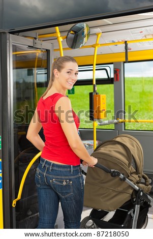 Young woman with a baby in a stroller getting into a bus on the bus station