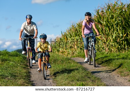 Family is cycling in summer - here mother, father and son