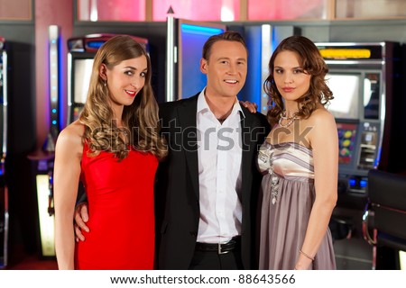Three friends - one man and two women - in Casino in a playful mood