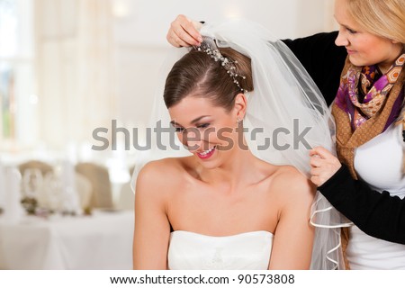 Stylist pinning up a bride\'s hairstyle and bridal veil before the wedding