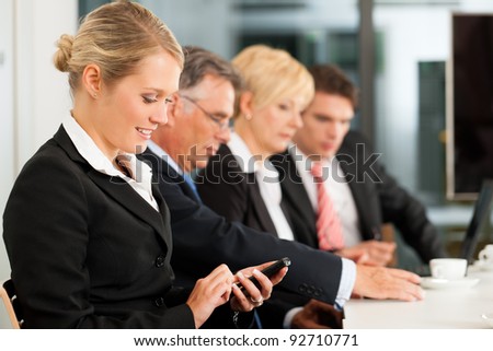 Business - team in an office; a woman is looking into the camera