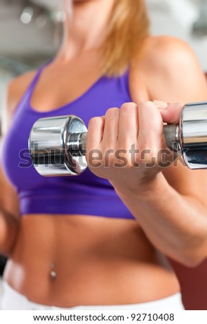 Young fitness woman is exercising with barbell in gym to strengthen the muscles