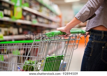 Cropped image of female shopper with cart at supermarket