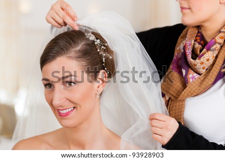 stock photo Stylist pinning up a bride's hairstyle and bridal veil before