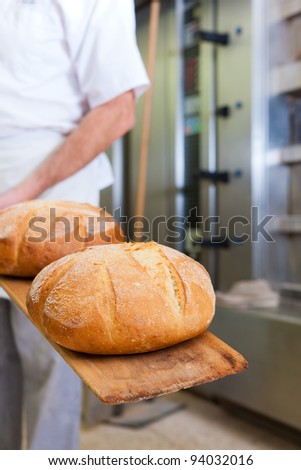 Male baker baking fresh bread in the bakehouse