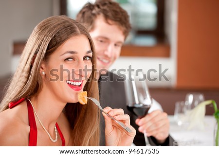 Portrait of a cheerful woman eating food with man having drink