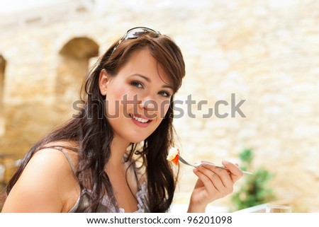 Young happy woman eating cake in the afternoon in front of a castle