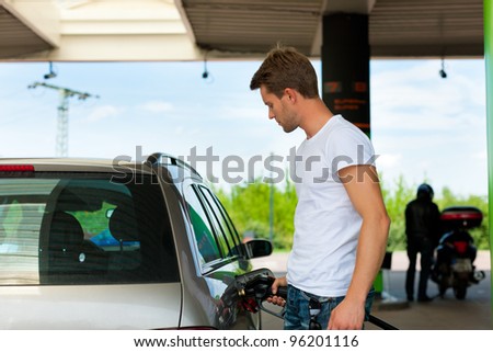 Refuel the car on a gas station; man holding the tap