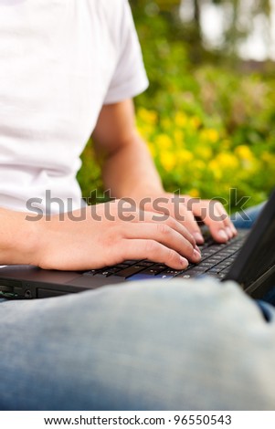 Man - only torso - is working on his laptop outdoors; presumably it is his garden