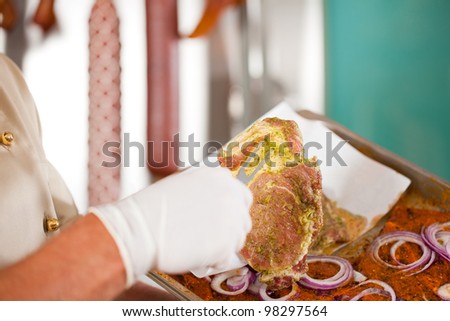 Working in a butchers shop - a butcher with raw meat (only hands to be seen)