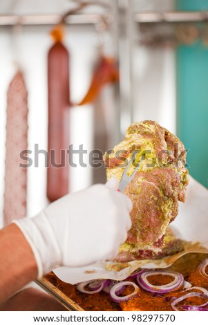 Working in a butchers shop - a butcher with raw pork meat (only hands to be seen)