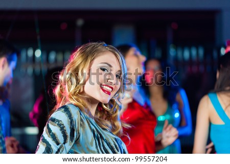 Clubbing and nightlife - Woman in club or bar having fun, in the background her friends