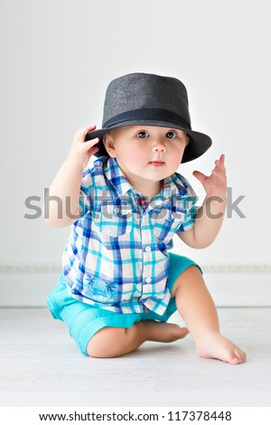 Cute baby sitting on the floor in a hat