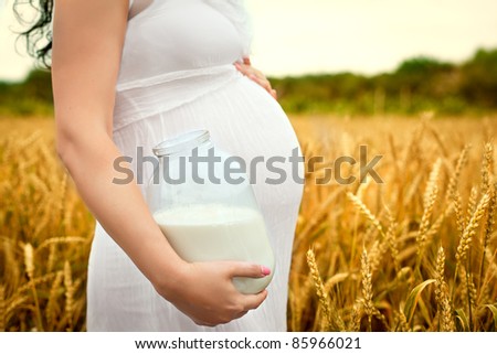 cute belly pregnant girl with a jar of milk in the