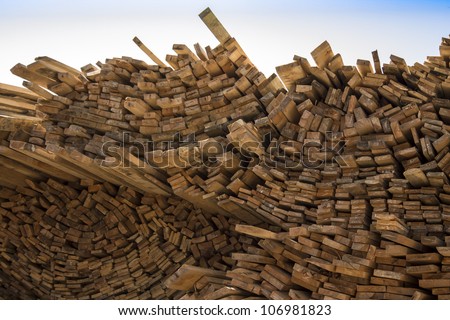 Wood fuel is eco friendly - stack of logs against bright blue sky with few clouds.