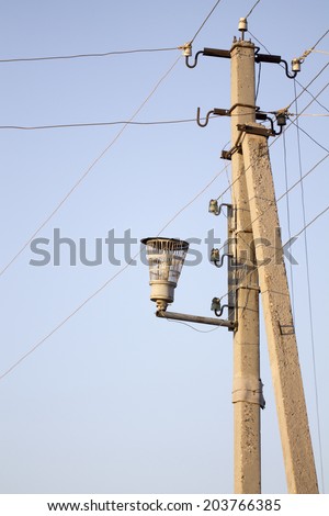 A convoluted mess of wires and cables clutter a wooden telephone pole and street lamp.