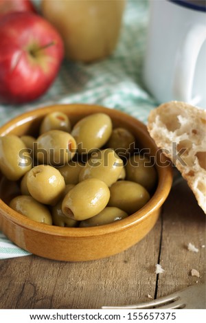 Pimento stuffed olives in a rustic mealtime setting.  Selective focus on front olive.