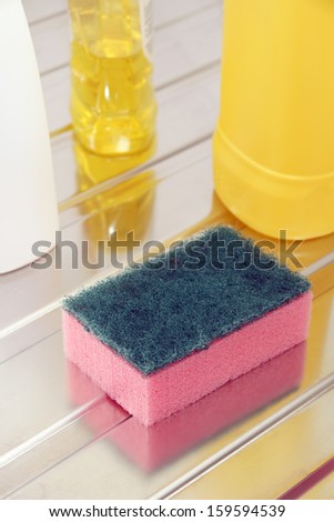 Nylon pan scourer and detergent bottles on a stainless steel drainer