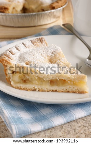 Slice of hot apple pie dusted with icing sugar