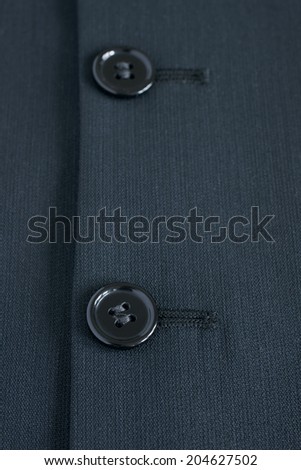 Black buttons against black suit fabric selective focus on bottom button