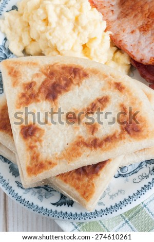 Irish potato farls or potato cakes with bacon and scrambled eggs