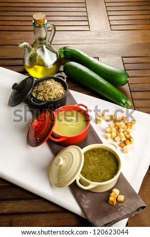 Cocottes with two kinds of vegetable cream and rice, fresh zucchini and croutons on background