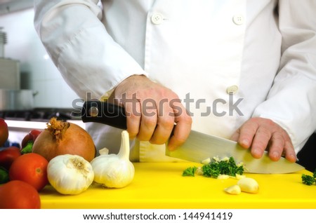 Vegetables on cutting board and chef hands detail, restaurant kitchen on background