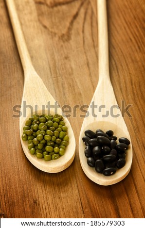 Green soybeans and mexican black beans on wooden background, biologic agriculture