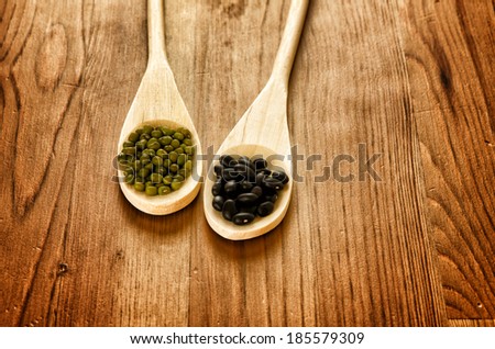 Green soybeans and mexican black beans on wooden background, biologic agriculture