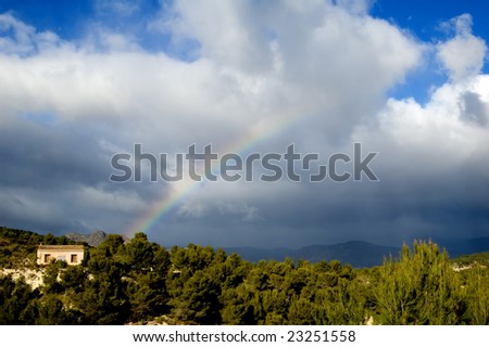 Rural landscape with trees, house and rainbow
