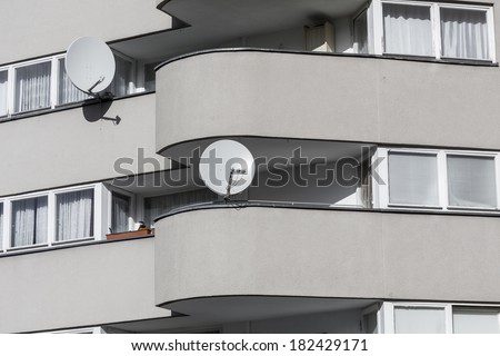 detail of a sparse gray house with two  satellite dishes.