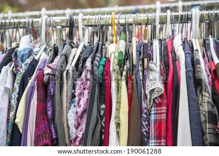 clothes on a rack in a flea market .