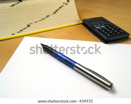 Blank paper and pen infront of calculator and book